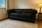 Chesterfield Sofa Loveseat Black shown in a realistic home living room setting